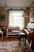 Zweisitziges Sofa am Fenster eines Londoner Hauses mit Klavier und Lampe England UK