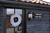 Floral wreath on glass paned door of creosote rural Suffolk home England UK