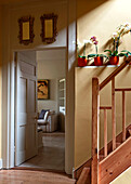 Wooden staircase with houseplants and view through doorway in rural Suffolk home England UK