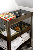 Folded towels and toiletries on antique storage trolley in London home, UK