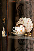 Tasse und Untertasse in einer Glasvitrine in einem Haus in Walberton, West Sussex, England, Vereinigtes Königreich