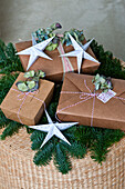 Gifts wrapped in brown card with stars on basket with sprigs of pine in Forest Row family home, Sussex, England, UK