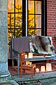 Fur throw on bench seat with lit candles, Forest Row family home, Sussex, England, UK