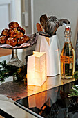 Pastries on cake stand with utensil holder and lit candle on kitchen counter in Paris apartment, France