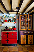 Colourful crockery with red oven in beamed kitchen of Essex home, England, UK