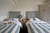 Striped duvets on twin beds with lighthouse on table in Buckinghamshire home, England, UK