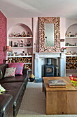 Black leather sofa with wooden coffee table in living room with pink recessed arches in Bovey Tracey family home, Devon, England, UK