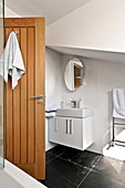 Wooden door open to white bathroom in Wadebridge home, Cornwall, England, UK