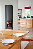 Lit fire in open plan dining room kitchen, contemporary home, Cornwall, England, UK