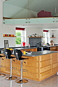 Black barstools with grey worktop in kitchen of contemporary home, Cornwall, England, UK