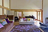 Contrasting sofas with floral patterned rug in open plan living room of contemporary Suffolk/Essex home, England, UK