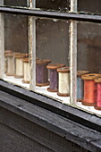 Fadenspulen auf der Fensterbank eines Hauses in Suffolk/Essex, England, UK