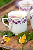 Cups with pink lemonade and posies of buttercups (Ranunculus) in Brecon, Powys, Wales, UK