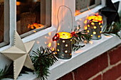 Beleuchtete Kerzen und Weihnachtsdekoration auf der Fensterbank eines Cottage in Shropshire, England, UK