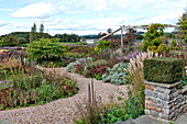 Variety of shrubs in rural garden with gravel paths in Blagdon, Somerset, England, UK