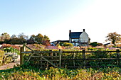 Rural farmhouse exterior with fence and large garden in Blagdon, Somerset, England, UK