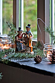 Spinning wheel figurines with pine cones and tealights on windowsill of Tregaron home Wales UK