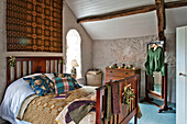 Gold and red wall hanging above wooden bed in whitewashed bedroom of Tregaron home Wales UK