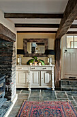 Cream painted sideboard in beamed room of Sherford barn conversion with patterned rug Devon UK