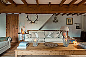 Books and lit candles on wooden coffee table in living room of Sherford barn conversion with wall-mounted antlers Devon UK