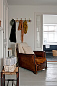 Brauner Ledersessel unter Kleiderhaken im Schlafzimmer eines Hauses in Crantock Cornwall England UK