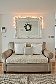 Lit lights on mirror above two seater sofa in Wadebridge home, North Cornwall, UK