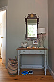 Mirror and lamp on table with seashells in hallway of family home, Cornwall, UK