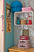 Suitcases and posters with blue paper cut bauble with silver metallic wallpaper in East Grinstead family home West Sussex England UK