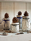 Pinecones on fabric covered jamjars on London shelf England UK