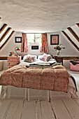 Double bed at window in timber framed bedroom of Cambridge cottage England UK