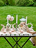 Osterhasen und silberne Kerzenständer mit Schnittblumen auf dem Gartentisch in Sussex England UK