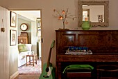 Grüne Gitarre und Klavier mit Blick durch die Tür zum Edworth-Wohnzimmer Bedfordshire England UK