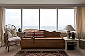 Striped cushion and binoculars on wooden bench seat in window of beach house Cornwall England UK