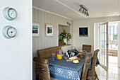 Breakfast table with blue tablecloth and wicker chairs in Penzance farmhouse kitchen Cornwall England UK