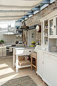 Weiße Küchenkommode mit freiliegender Steinwand in Küchenerweiterung eines Bauernhauses in Penzance, Cornwall, England, UK