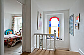 Hall landing with stained glass and view into bedroom of holiday cottage Cornwall UK