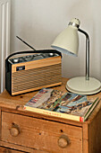 Radio book and bedside lamp on wooden chest of drawers in Cornwall cottage Cornwall UK