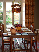 Leaf decorations above wooden dining table with chairs and seat cushions in UK home