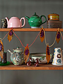 Verschiedene Teekannen mit Blattdekoration auf einem Holzregal in einem Haus in Großbritannien