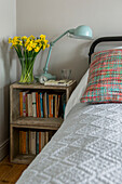 White covers on metal framed bed with crate storage in St Ives home Cornwall England UK