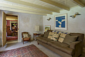 Vintage-Lampen und moderne Kunst über einem braunen Sofa im Wohnzimmer eines Bauernhauses in Helston, Cornwall UK