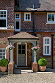 Hängende Körbe auf der Eingangsveranda eines um 1880 erbauten viktorianischen Hauses im Lutyens-Stil, das unter Denkmalschutz steht (Grade II), in Godalming Surrey UK