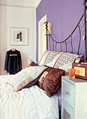 Schlafzimmer mit eisernem Bettgestell und lila gestrichener Wand