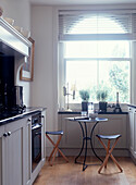 Küche mit großem Rundbogenfenster und rundem Tisch mit Stühlen