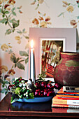 Lit candle with paperback books on side table in Shropshire cottage England UK