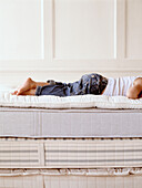 Child lying on stack of mattresses with topper
