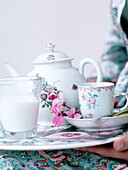 Frau hält Porzellan-Teeservice auf Tablett