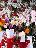 Dahlias in white buckets on plant stand with floral wallpaper