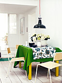 Schwarze Pendelleuchte über dem Esstisch mit Blumen und grünem Tuch