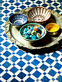 Türkisfarbene Edelsteine in handbemalten marokkanischen Schalen mit Tablett auf Tischplatte in Nordafrika